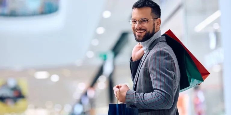 Young happy man shopping at the mall and looking at camera