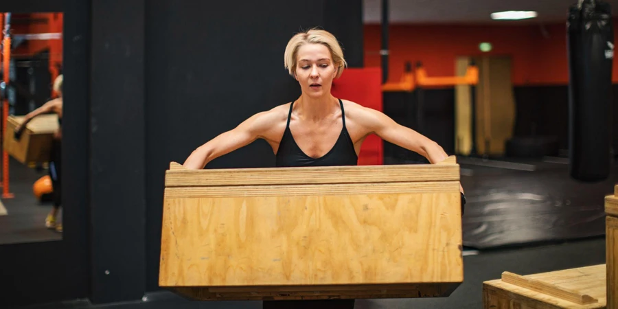 a woman athlete carries the plyo box