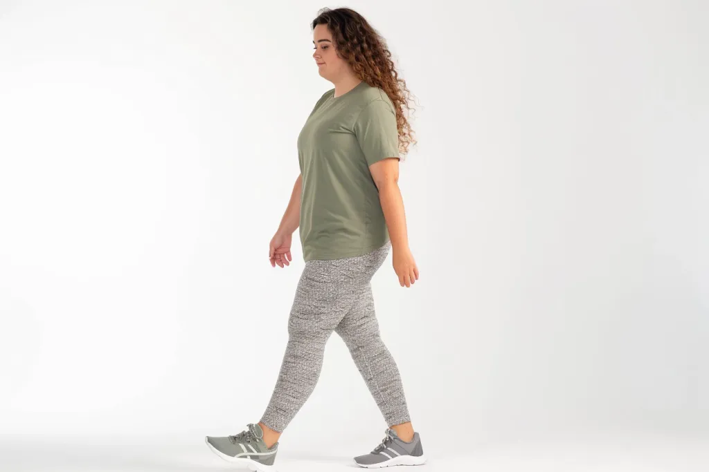an attractive young woman in green tshirt and grey pattern leggings