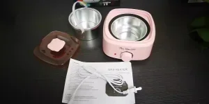 Un calentador de cera rosa sin caja sobre una mesa