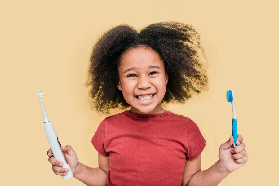 Child holds manual and electric sonic toothbrushes