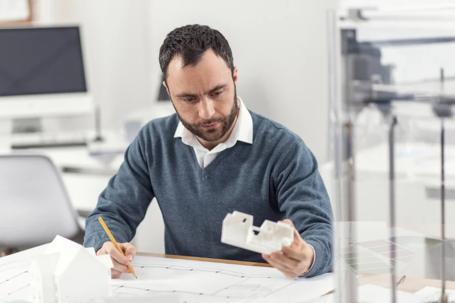 Engineer looking at blueprints and 3d model of design