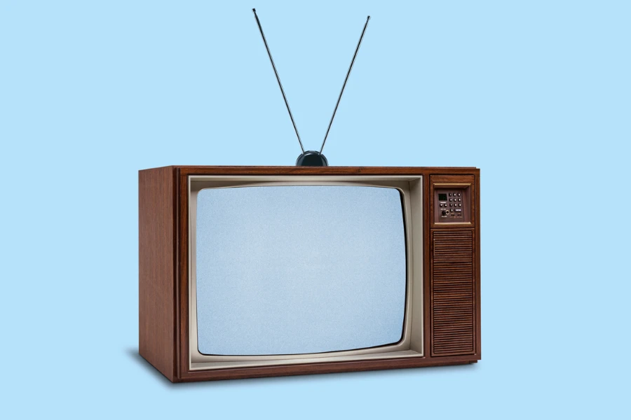 A retro 1970's television with rabbit ears on top on a blue background