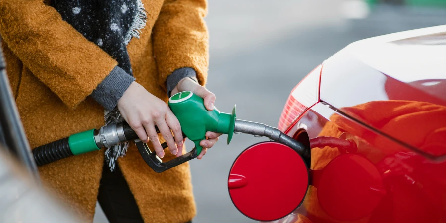 Close up shot of a young businesswoman filling her car with fuel before work