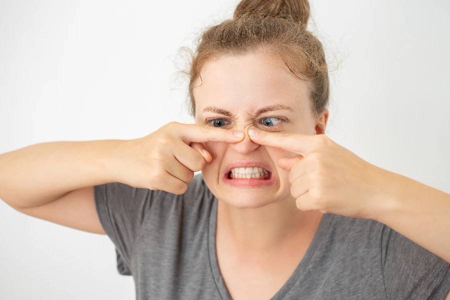 Young caucasian woman squeezing a pimple on her nose
