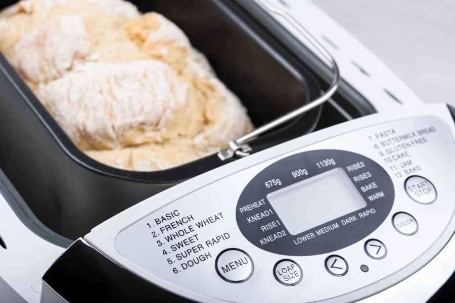 Homemade white flour bread baked in bread maker with digital display
