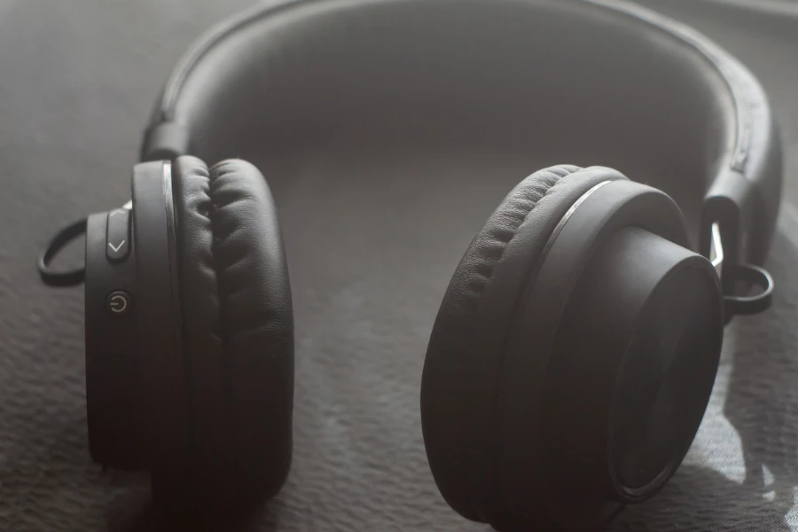 Black wireless headphones on a black textured background with sun rays