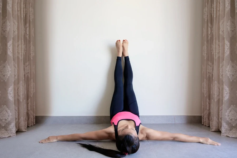 Yoga woman feet up relaxing in room on wall background