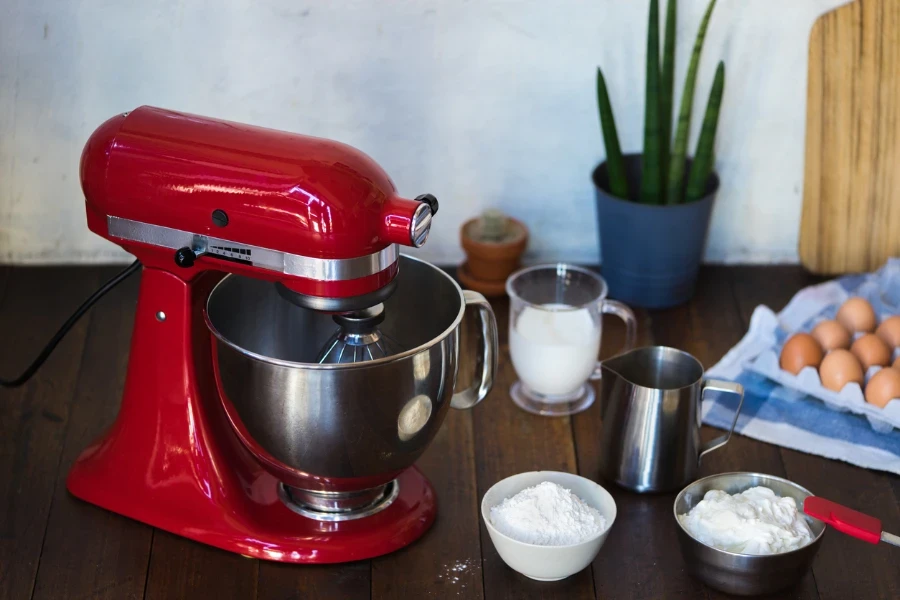 Closed standing mixer on wooden table with ingredients
