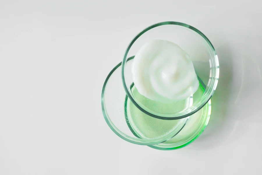 Glass petri dishes with various cosmetic products on white background
