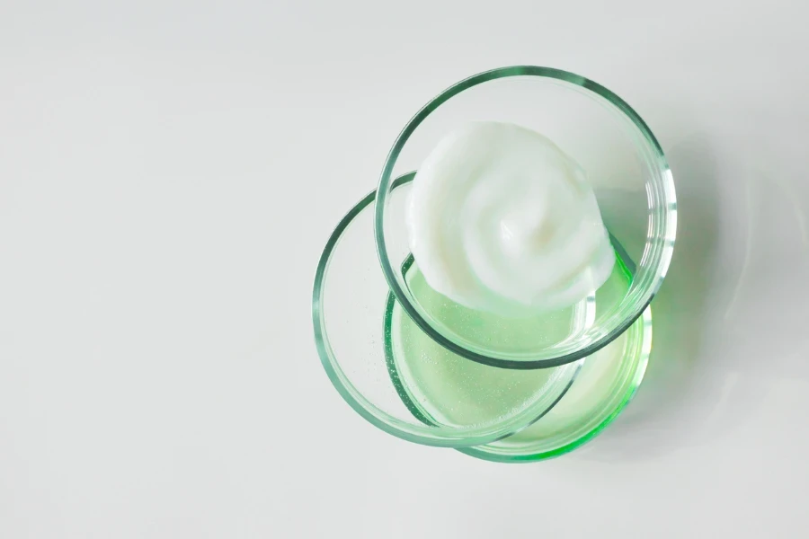 Glass petri dishes with various cosmetic products on white background
