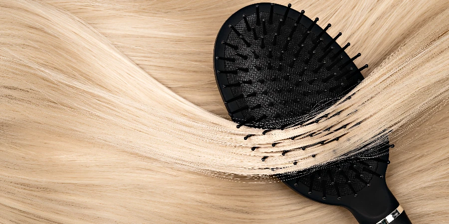 Closeup of Black hair brush lying on straight shiny blond hair