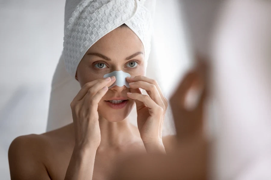 Focused young beautiful woman with towel on head applying cleaning strip
