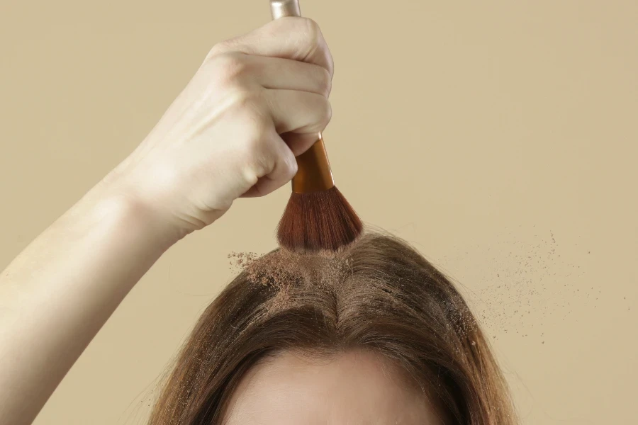 Close up view at woman applying natural dry shampoo on hair roots
