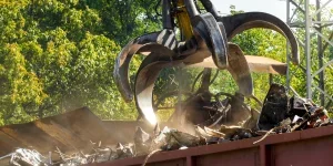 Claw gripper working on metal scrapyard with old rusty pieces