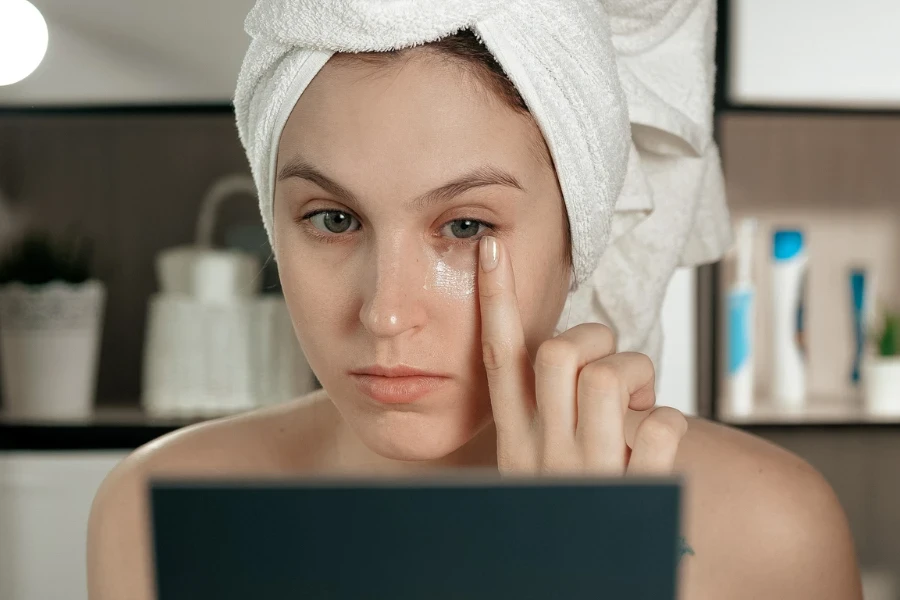 a young caucasian woman touching a skin of her face while applying the cream
