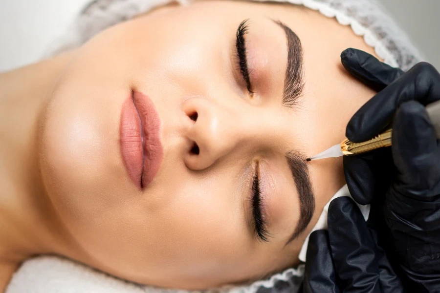 Top view of permanent makeup on eyebrows of young caucasian woman by special tattoo tool
