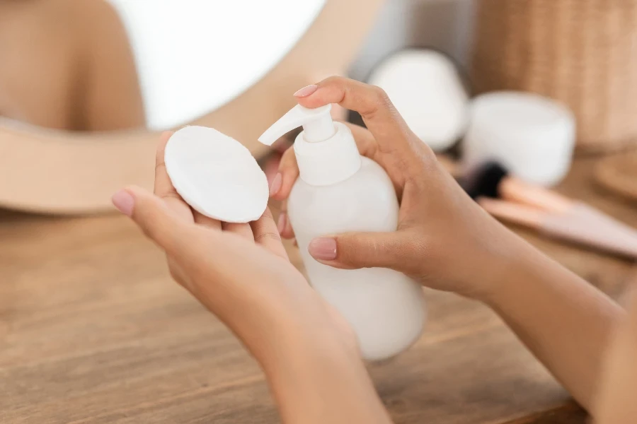 Unrecognizable woman applying makeup remover on cotton pad
