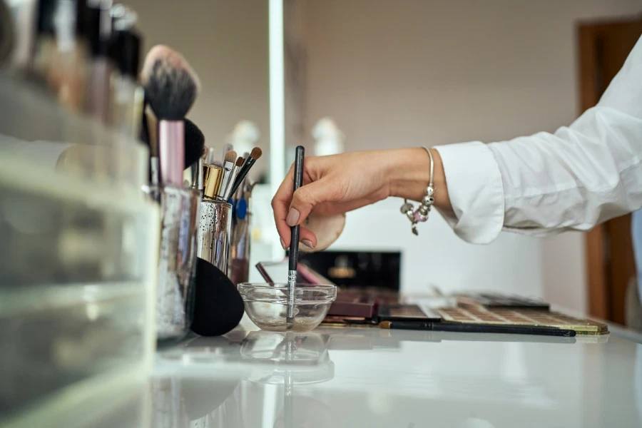 Make up artist choosing the products and brush on her make up desk in her modern make up studio
