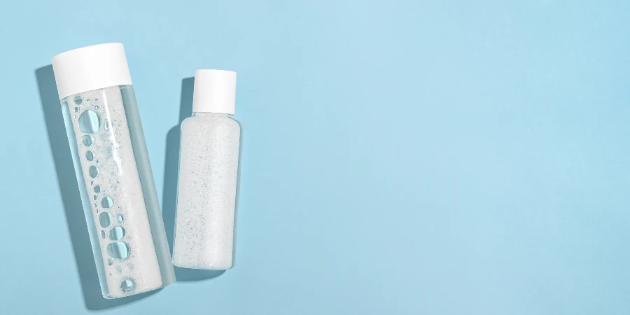 micellar water in white plastic bottles on a blue background top view