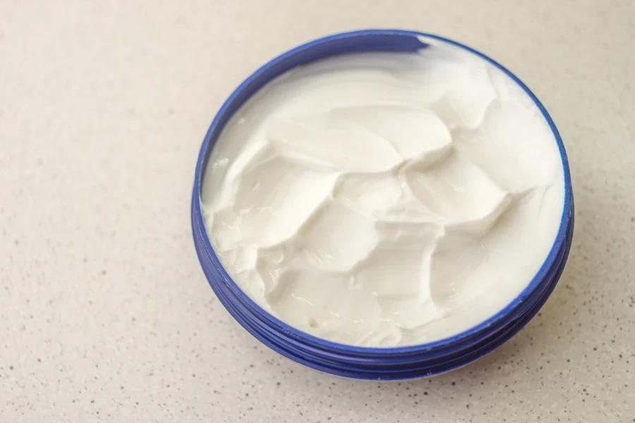 Open blue container with white cream on a marble table