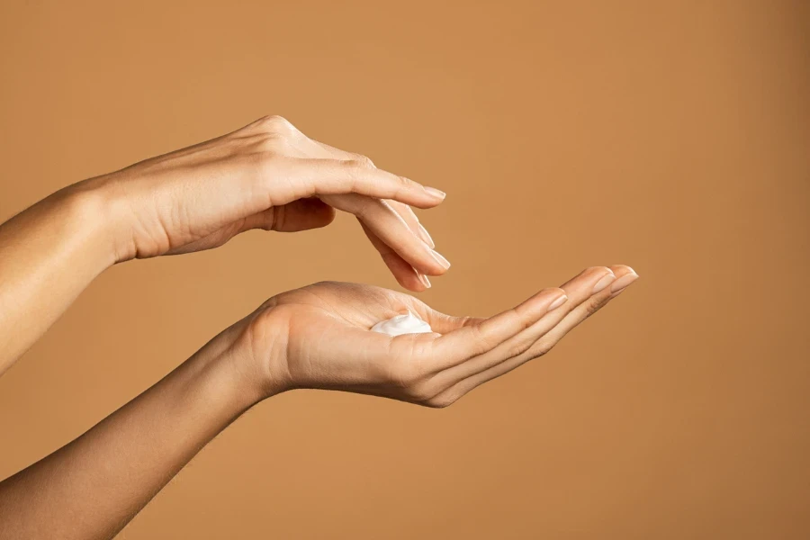 Close up shot of beautiful female hands holding and applying moisturiser