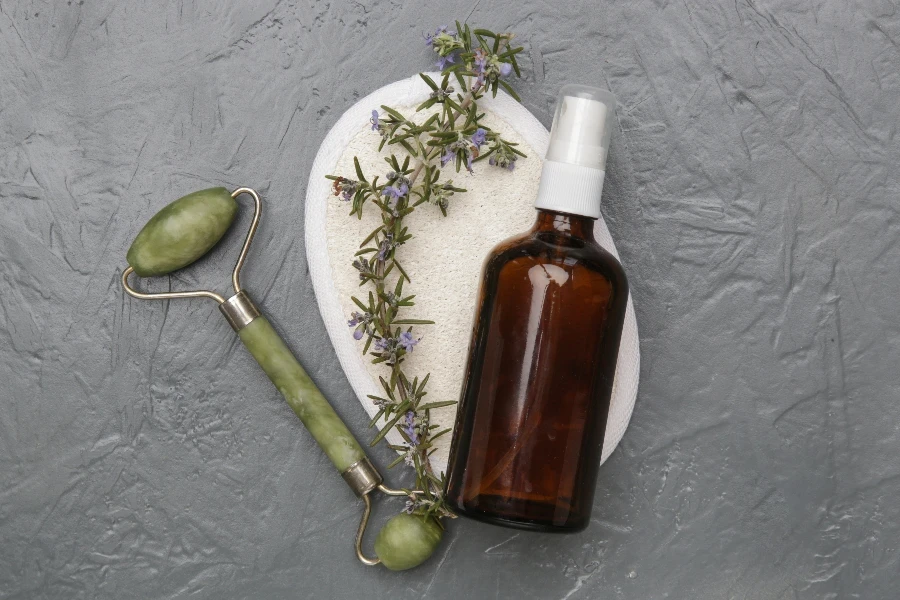 Facial serum and jade roller on gray background
