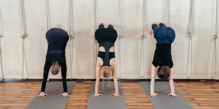 Women learning to stand on hands near wall
