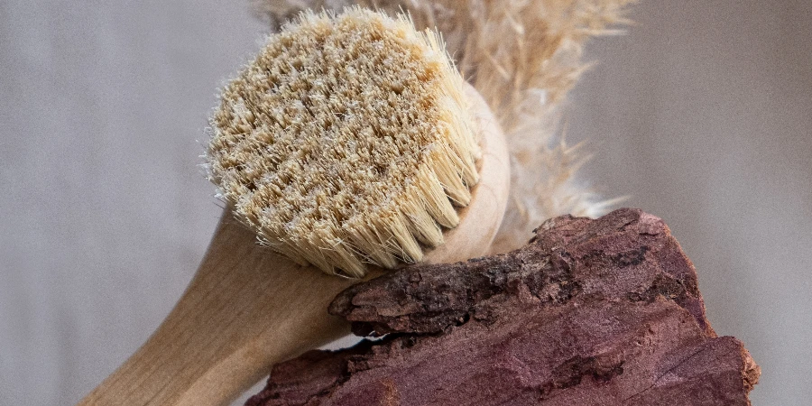 Facial massage brush with natural bristles on a linen background with bark and dried flowers