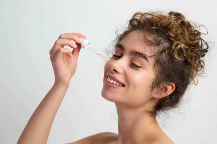 Shot of beautiful woman applying serum to her clean face skin against a face wrinkles