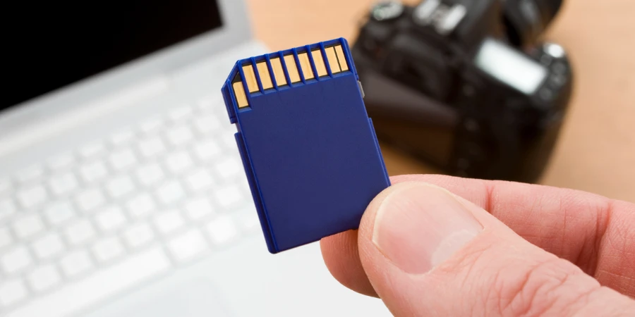 Close up of SD card with computer and camera in background