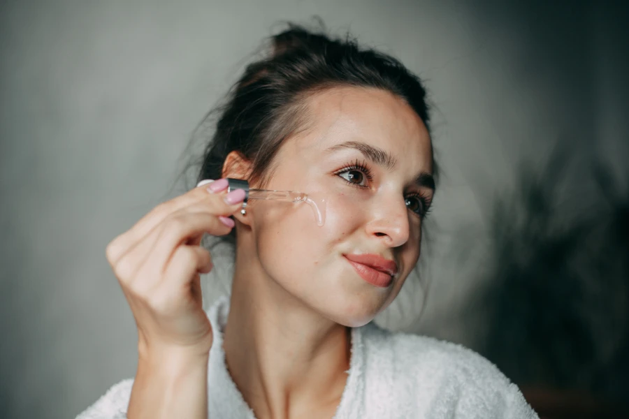 woman with long hair in a bun 30 years old applies serum
