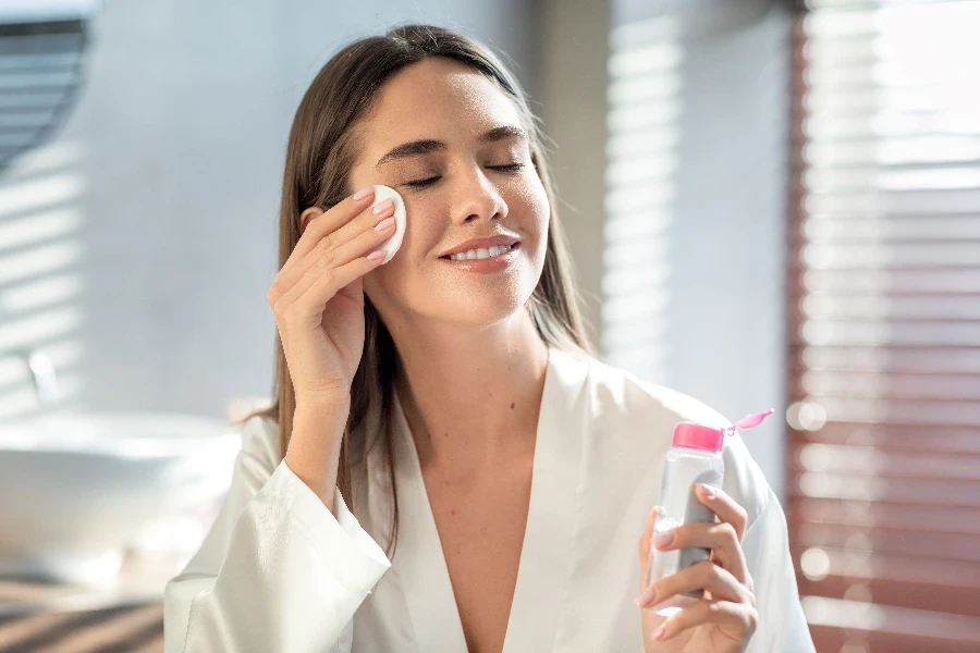 Beautiful Smiling Woman Cleansing Skin With Micellar Water And Cotton Pad
