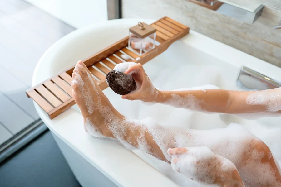 Woman using foot scrub pumice stone to scrub her feet
