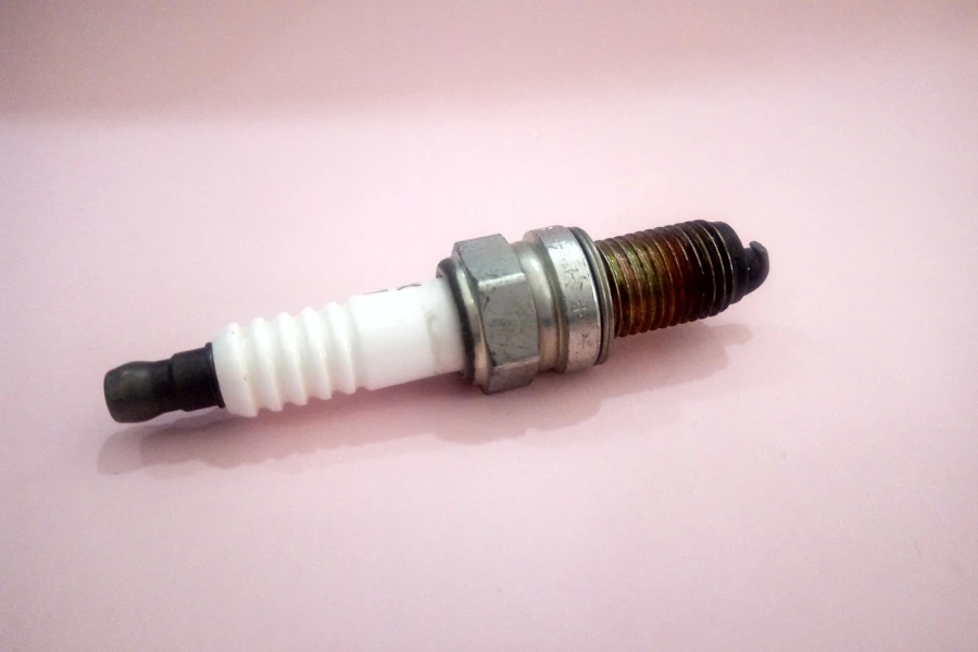 A motorcycle spark plug with a faded pink background