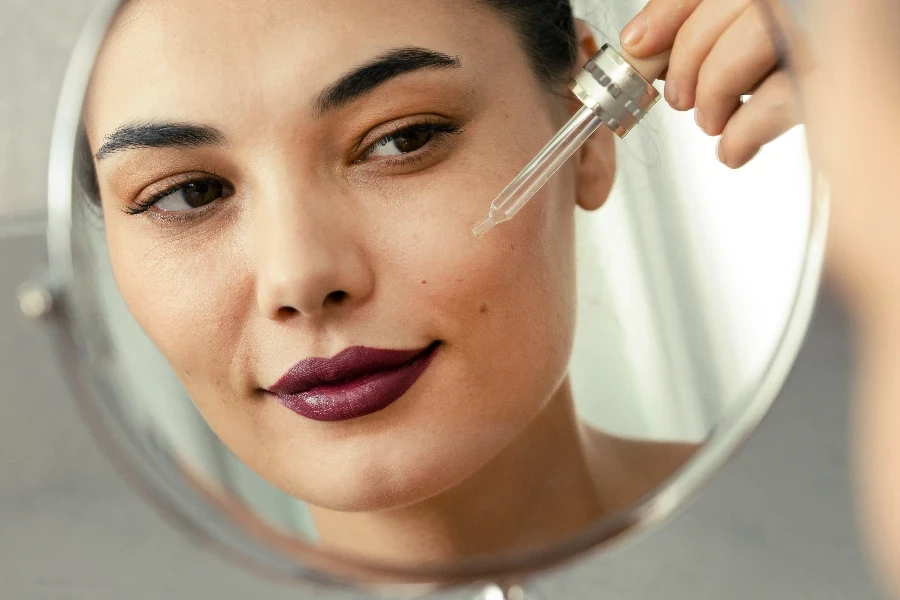 Woman applying serum to her clean face skin against a face wrinkles