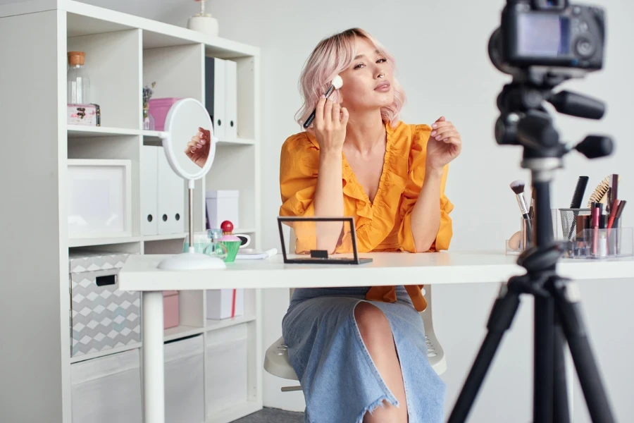 Young beautiful blond asian woman is recording make up tutorial video for beauty blog