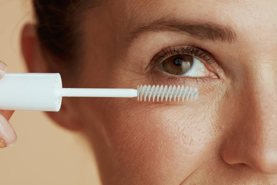 Closeup on modern female with lash gel mascara against beige background
