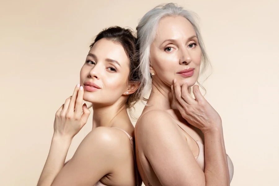 Elderly and young women with smooth skin and natural makeup standing back-to-back
