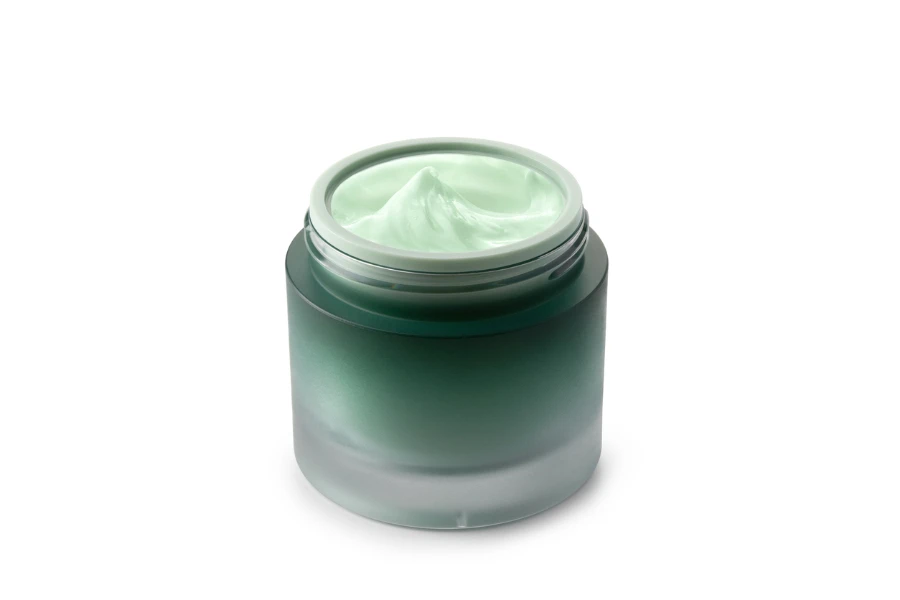 green beauty cosmetic cream in green glass jar on white background

