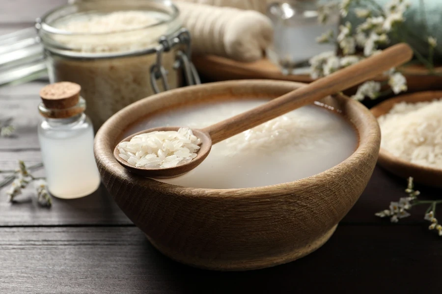 Bowl with soaked rice and spoon on wooden table
