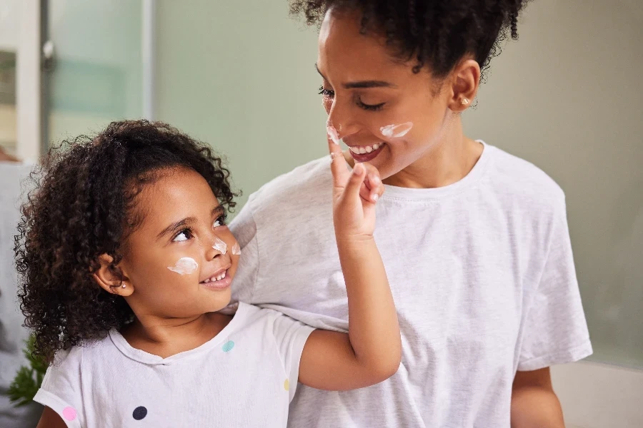 mother and girl bond in bathroom together in the morning with skin cream