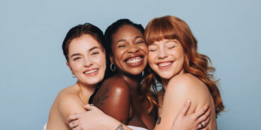 Group of happy women with different skin tones smiling and embracing each other