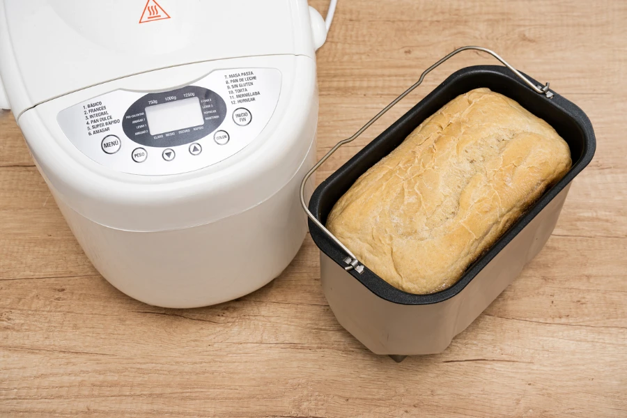 A Bread mold inside the kneading barrel next to the domestic bread machine
