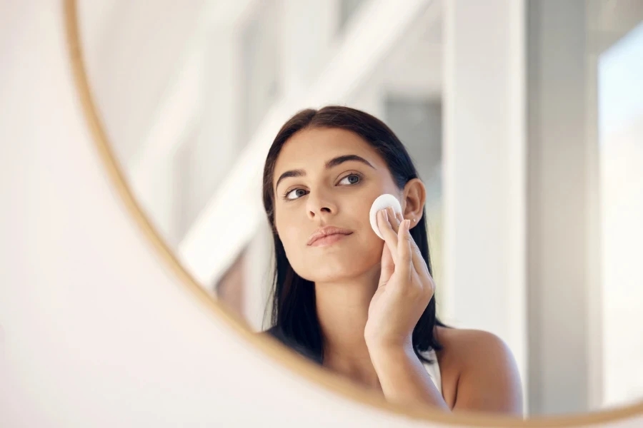 beauty and mirror with a woman cleaning her skin in the bathroom
