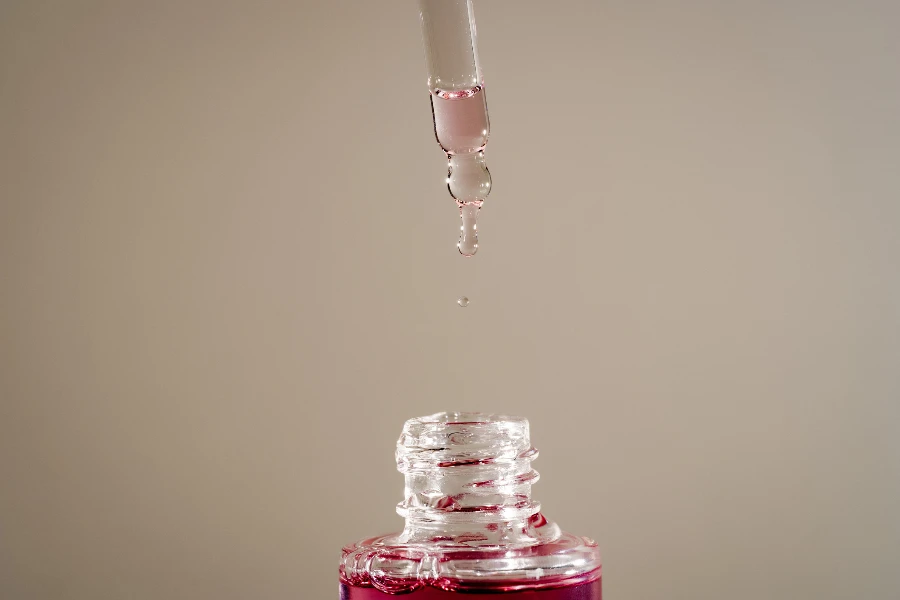 Pink face oil drop from glass pipette dropper
