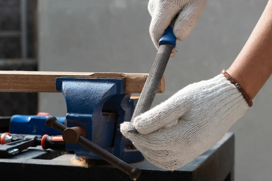 Senior man is using rasp on wood for assembling hammer handle
