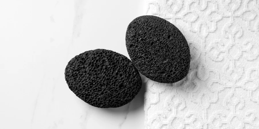 Black volcanic pumice stone lies on the table next to a white towel