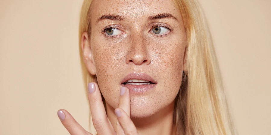 Woman with freckles touching her lip with a finger