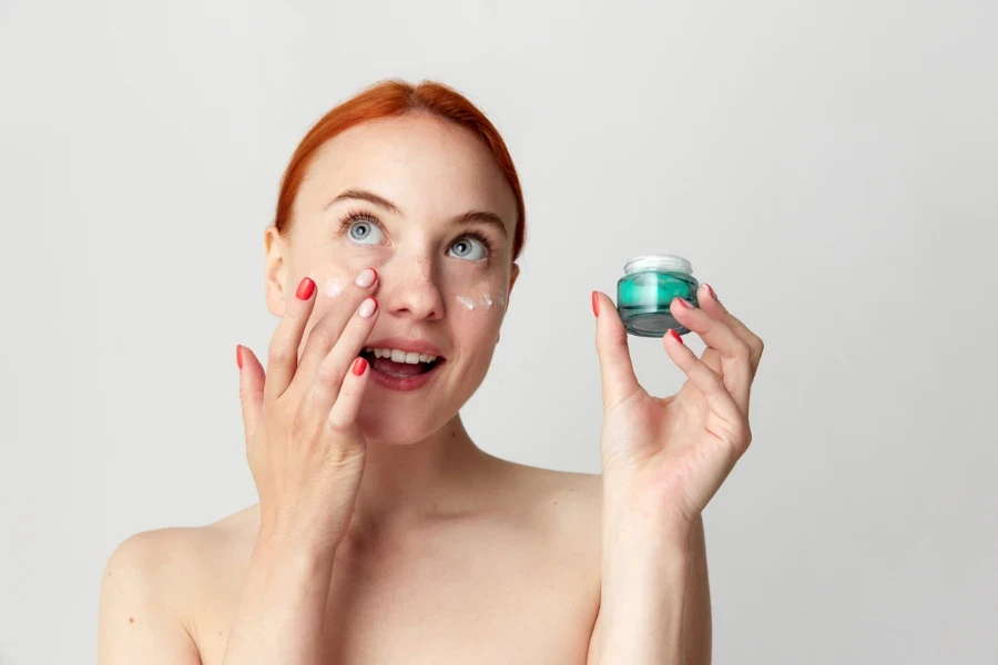 Beautiful mature woman applying facial cream under the eye.
